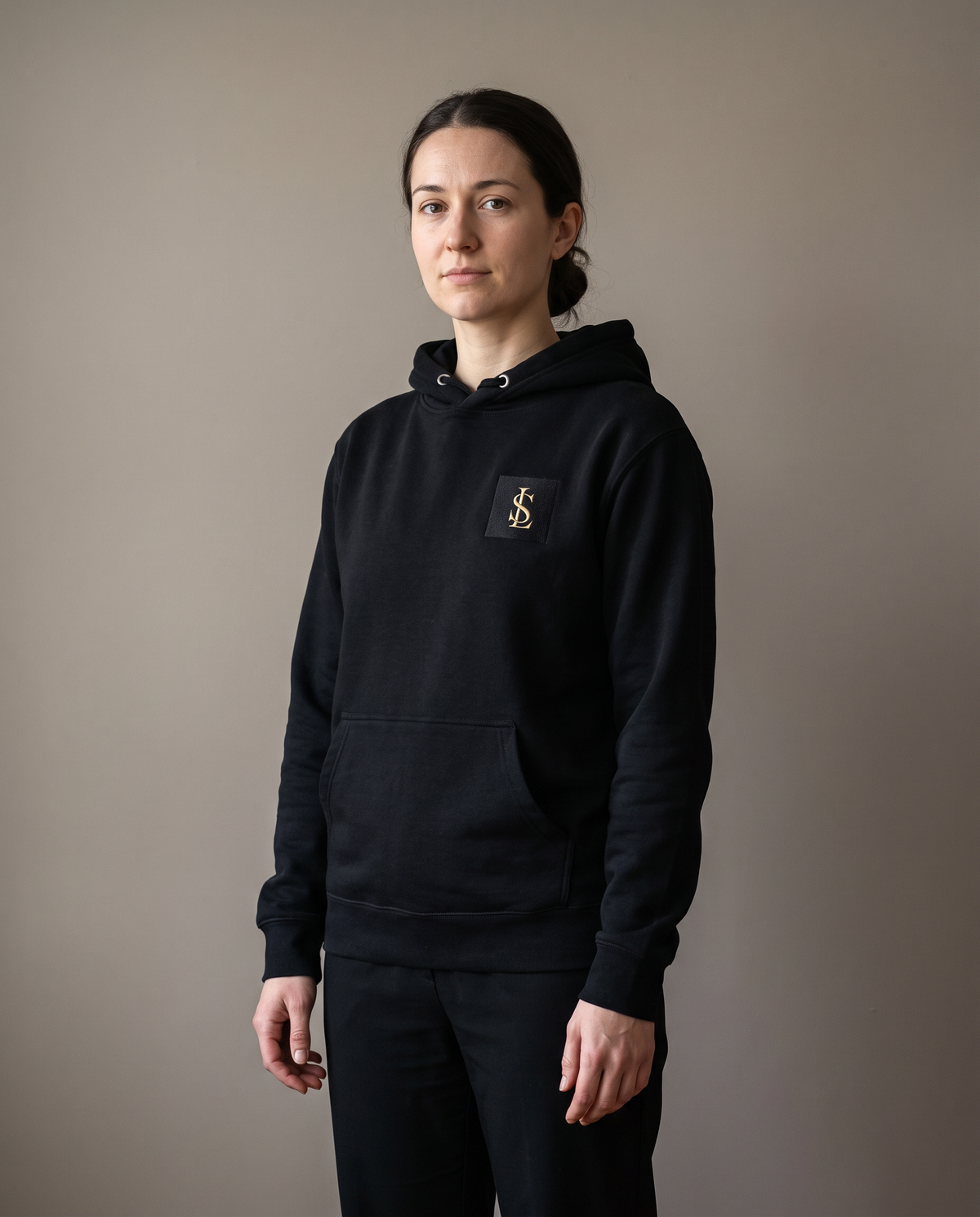 Signature Hoodie in black worn by a woman, studio view