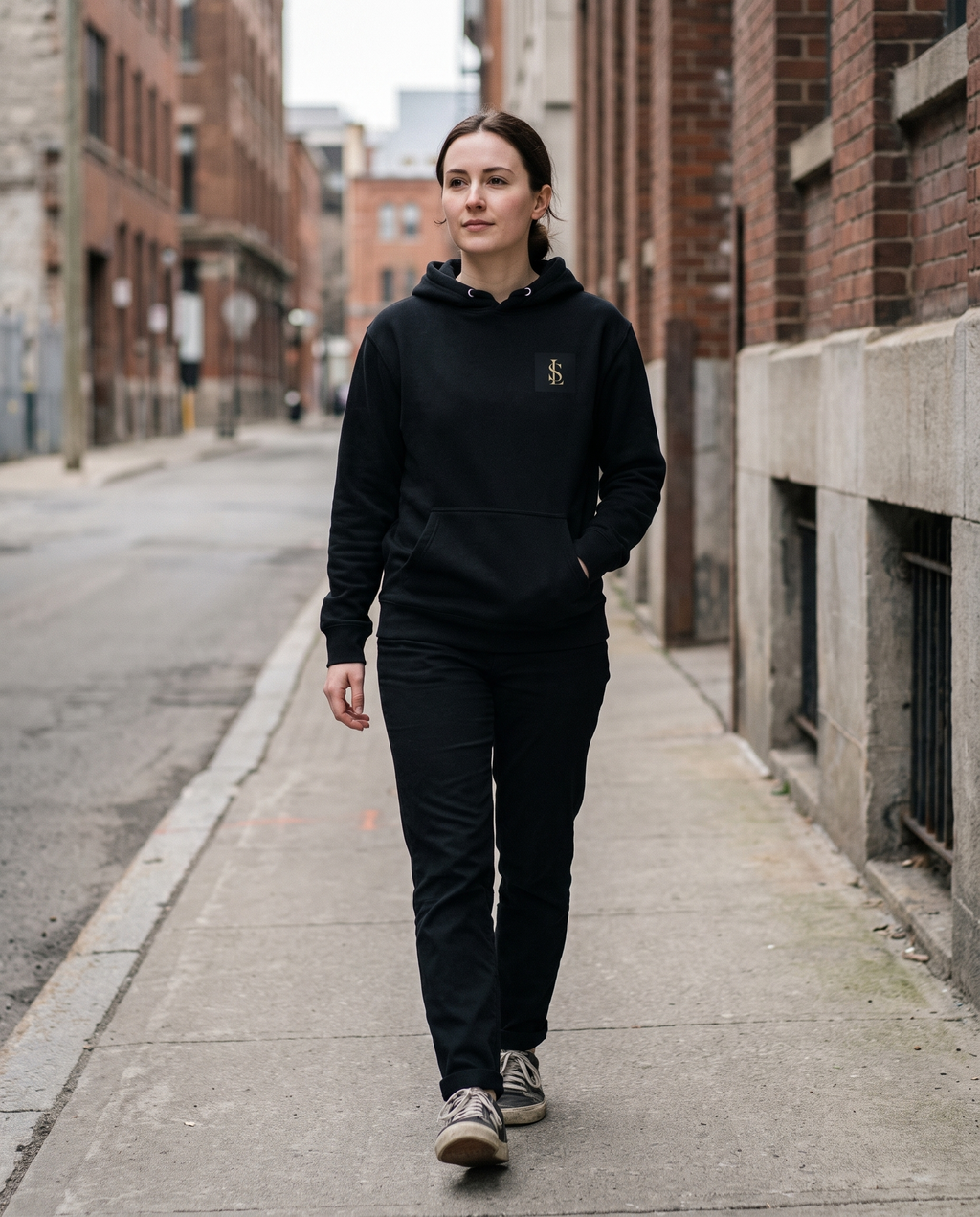 Signature Hoodie in black worn walking on a city street